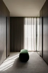 A modern interior space featuring light-colored textile curtains and warm lighting.