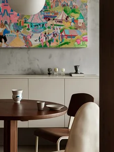 A modern interior space featuring a wooden table with a bowl and cup, complemented by a colorful painting on the wall.