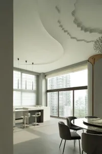 Modern kitchen and dining room with white marble countertops and glass partition.