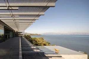 A modern residential interior with a concrete poolside overlooking the ocean.