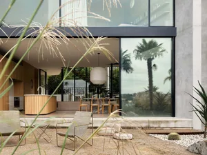 A modern residential interior featuring a concrete material with natural light streaming through large windows and a minimali