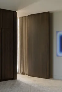 Modern minimalist residential interior featuring a large wooden sliding door and sheer curtains.