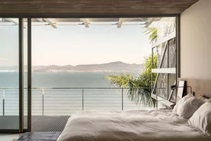Modern bedroom overlooking the ocean with a king-sized bed and minimalistic design.