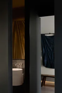 A minimalist bathroom with a metal bathtub, a blue towel hanging on the wall, and a wooden floor.