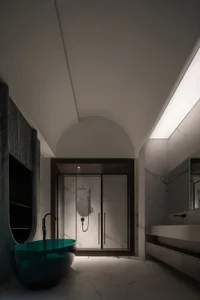 A modern bathroom featuring marble walls and glass shower enclosure.