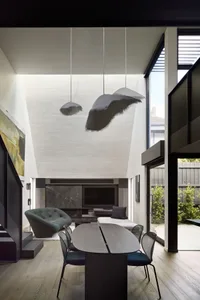 A modern dining room with a wooden table and chairs, featuring a stylish pendant light fixture and a view of the outdoor pati