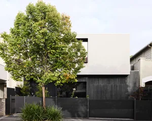 A modern residential home with white concrete exterior and black wooden accents.