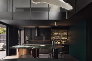 A modern residential kitchen featuring marble countertops and black metal fixtures.