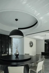Modern minimalist dining room with black table, chairs, and metallic vase.