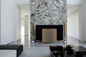 A minimalist living room with marble walls and a black coffee table.