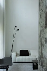 A minimalist living room featuring a white leather sofa with a black throw pillow, a marble side table, and a floor lamp with