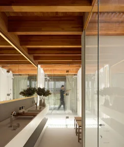 Modern bathroom with wooden beams, glass walls, and a minimalist design.
