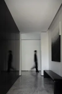 A modern hallway with minimalist design, featuring sleek black and white color scheme and a combination of concrete and glass