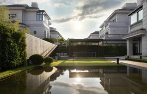 A modern landscape design featuring a water feature surrounded by well-manicured greens and high-end residential architecture