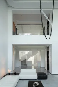 A modern, white and concrete residential living room with minimalist furniture and sleek lighting.
