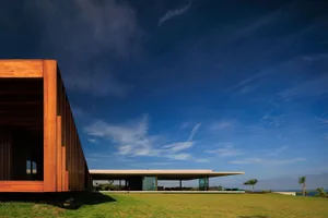 A modern villa with wood and glass exterior features large windows and a minimalist design.