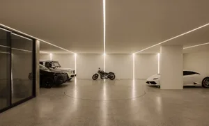 Minimalist style garage with circular concrete floor, concrete walls, and modern vehicles.