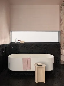 Contemporary bathroom featuring a freestanding tub, pink hand towel, and black terrazzo tiles.