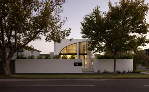 Modern house with minimalist design, white facade, and glass windows.