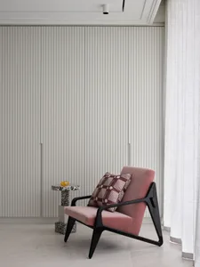 A modern living room featuring a pink cushioned chair, a small patterned side table, and vertical slat wall panels.