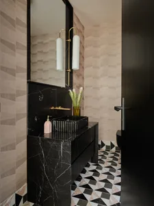 Modern bathroom with black marble sink, geometric floor tiles, and beige textured walls.