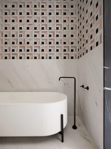 Modern bathroom with white marble tub and geometric tile pattern.