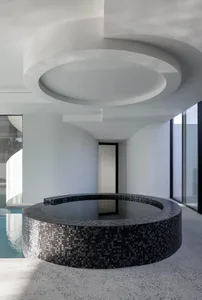A modern minimalist spa interior featuring a circular tiled spa