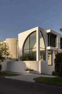 A modern residential building with a concrete exterior and large glass windows.