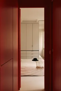 A minimalist bedroom with a white bed and a hat on it.