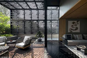 A minimalist living room featuring wood flooring, glass walls, and metal furniture.
