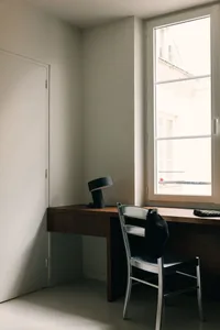 A minimalist working space featuring a wooden desk and chair.