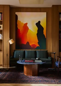 Modern living room featuring a large, colorful abstract painting with dark silhouettes against a gradient background, flanked