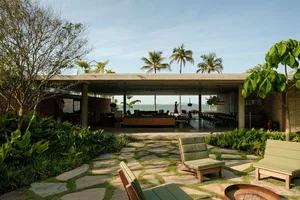 A modern residential patio featuring stone floors, wooden furniture, and concrete structures.