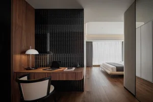 A modern minimalist bedroom with a wooden desk, chair, and floor, featuring a bed with a minimalist design.