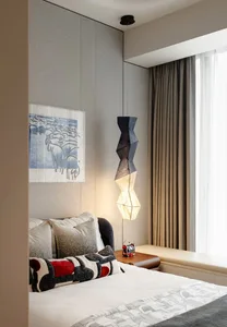 A modern bedroom with a fabric lamp hanging above the bed, surrounded by curtains and pillows.