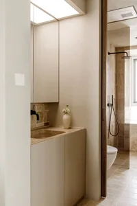 Modern bathroom featuring a sleek, minimalist design with beige marble countertops and matching beige marble tiles.