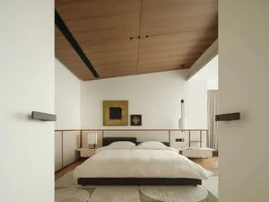 Modern minimalist bedroom featuring a white upholstered bed with an upholstered headboard, a wooden-paneled ceiling, pendant