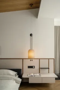 Minimalist bedroom with modern white furniture and pendant light fixture.