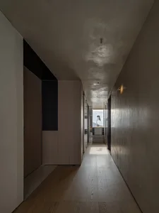 A modern corridor featuring wooden flooring and walls, with a view of the outdoors through glass doors.
