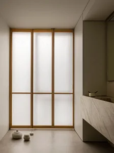 Minimalist bathroom featuring frosted glass walls, a floating marble vanity, and small ceramic vases on the floor.