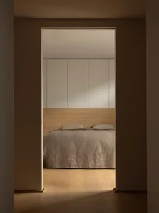 A minimalist bedroom with natural wood and light-colored textiles, showcasing a serene and simple design.