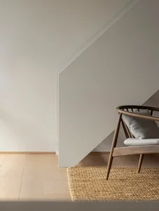 A minimalist living room featuring neutral-toned furniture and a wooden floor with a textured rug.