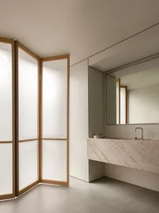 Modern bathroom featuring minimalist design with marble countertop, frosted-glass partitions, and wooden accents.
