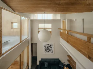 A modern living room featuring black furniture, a white paper lantern, and wooden accents.