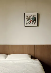A minimalist bedroom featuring a wood headboard and white bedding.