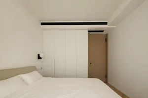 A minimalist modern bedroom with white walls and furniture, featuring a white bed with minimalist design.