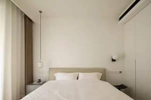 Modern minimalist bedroom with a bed, nightstand, and white walls.
