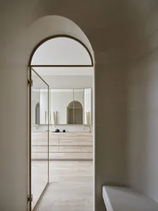 Modern, minimalist bathroom with marble walls and gold accents.