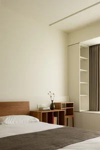 Minimalist bedroom with wooden furniture and white bedding.