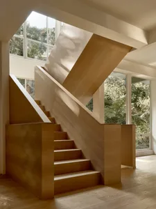 Modern interior with wooden stairs and large windows.